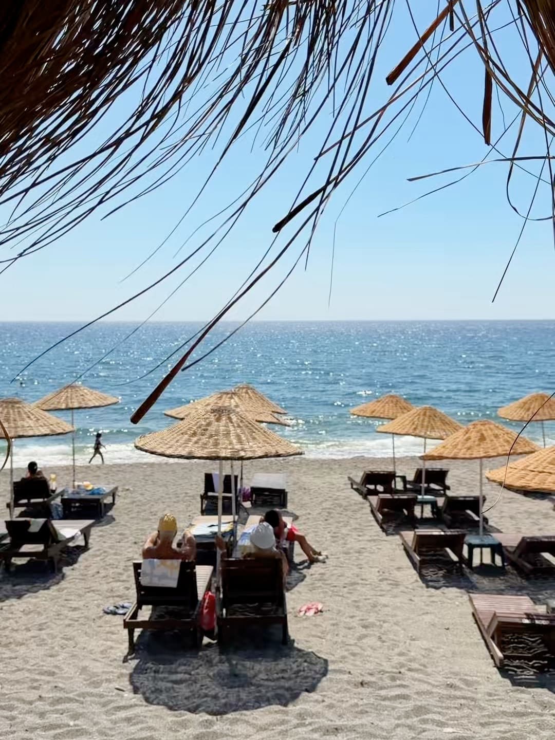 Plajda şemsiyeler, şezlonglar ve deniz
